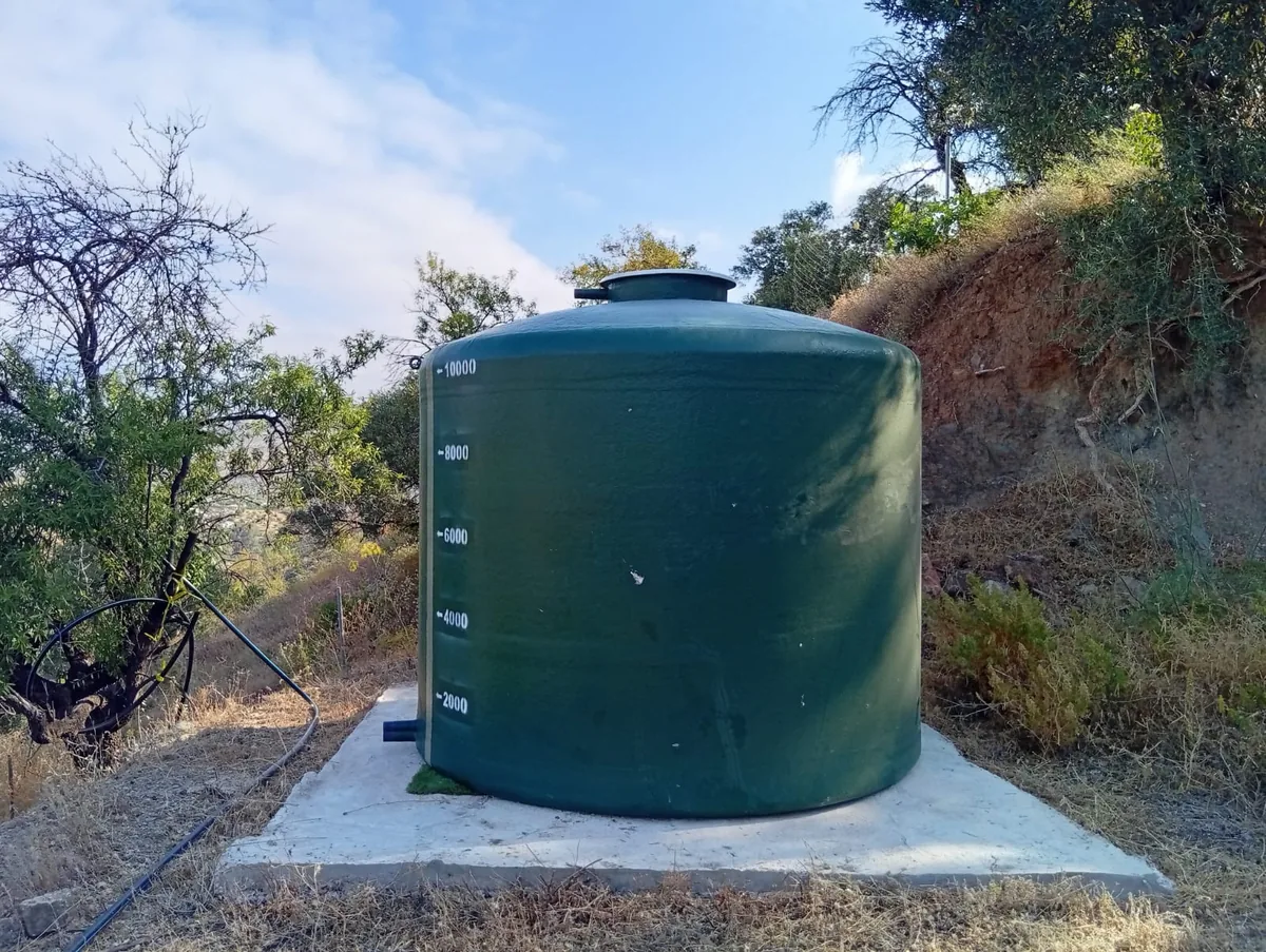 Depósito vertical de poliéster de base plana, de color verde, instalado sobre una solera de hormigón