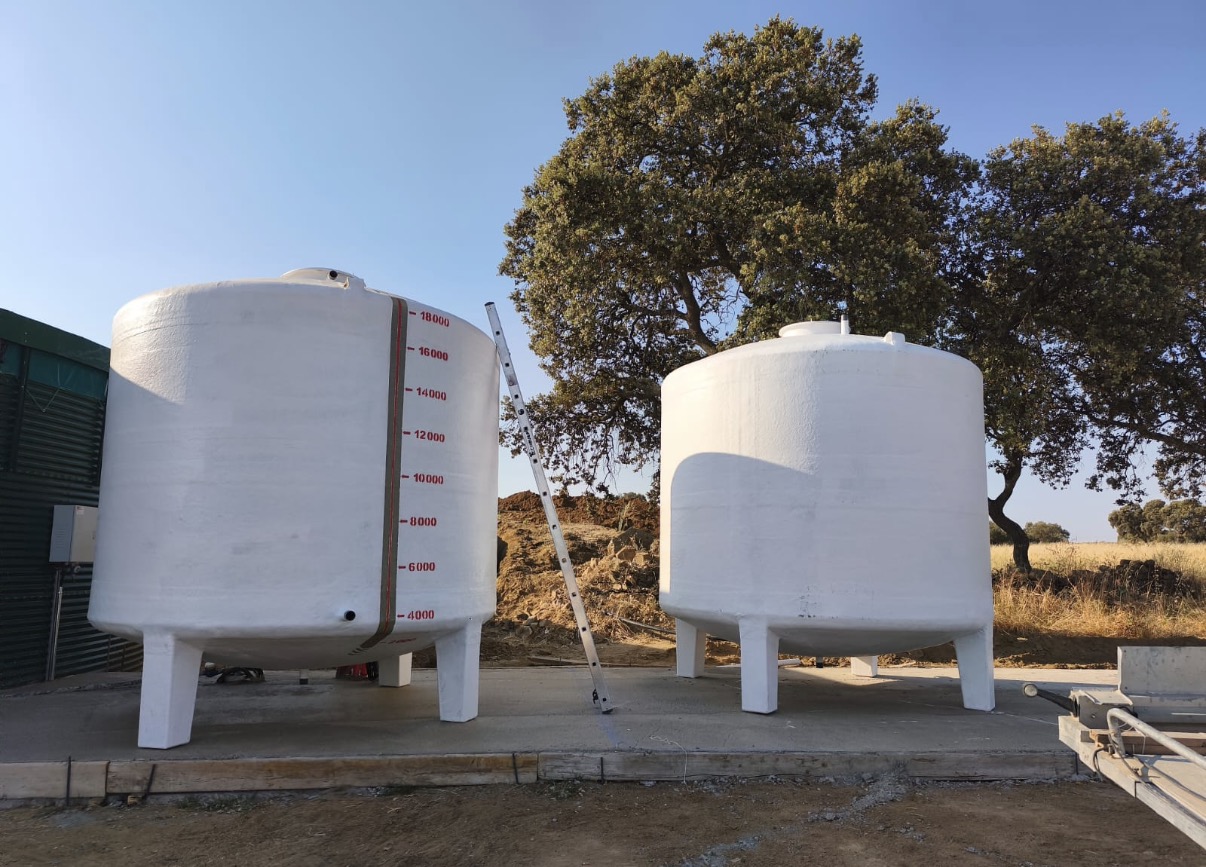 Dos depósitos verticales de poliéster blancos con apoyos, instalados sobre una solera de hormigón