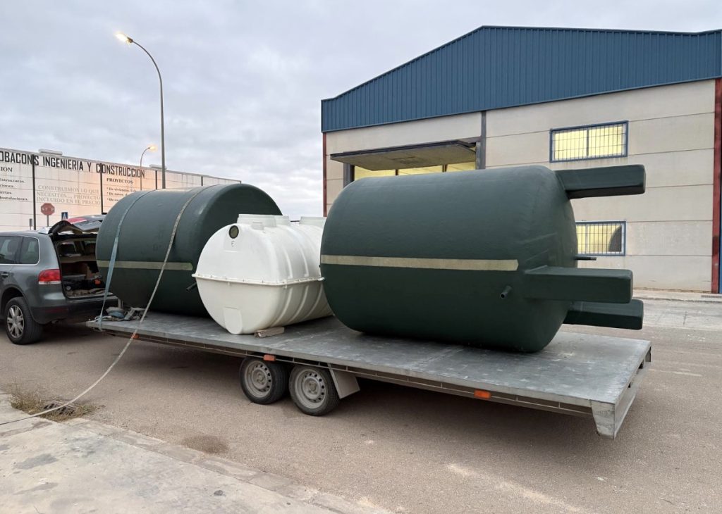 Depósitos verdes y una fosa blanca de poliéster preparados para transporte en un remolque