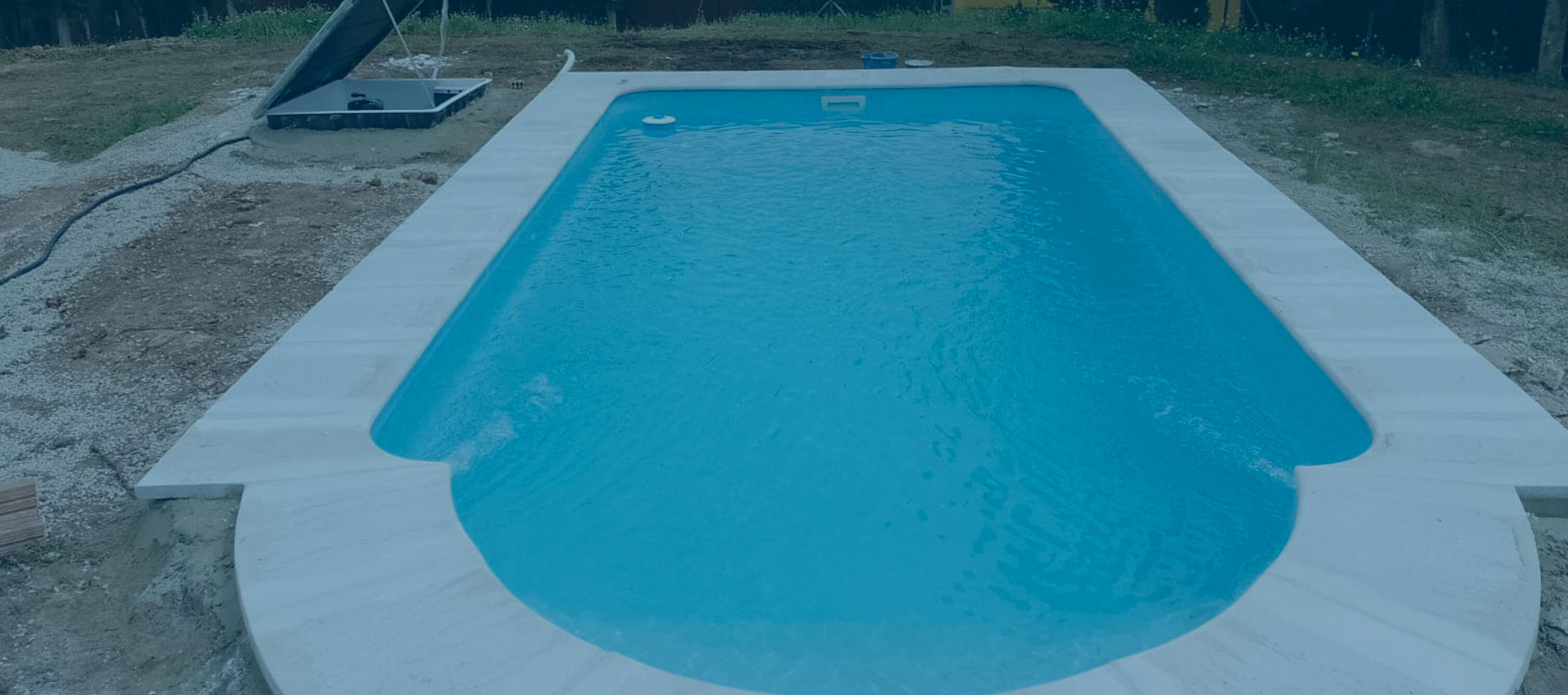 Piscina de poliéster instalada en exterior con agua y borde perimetral